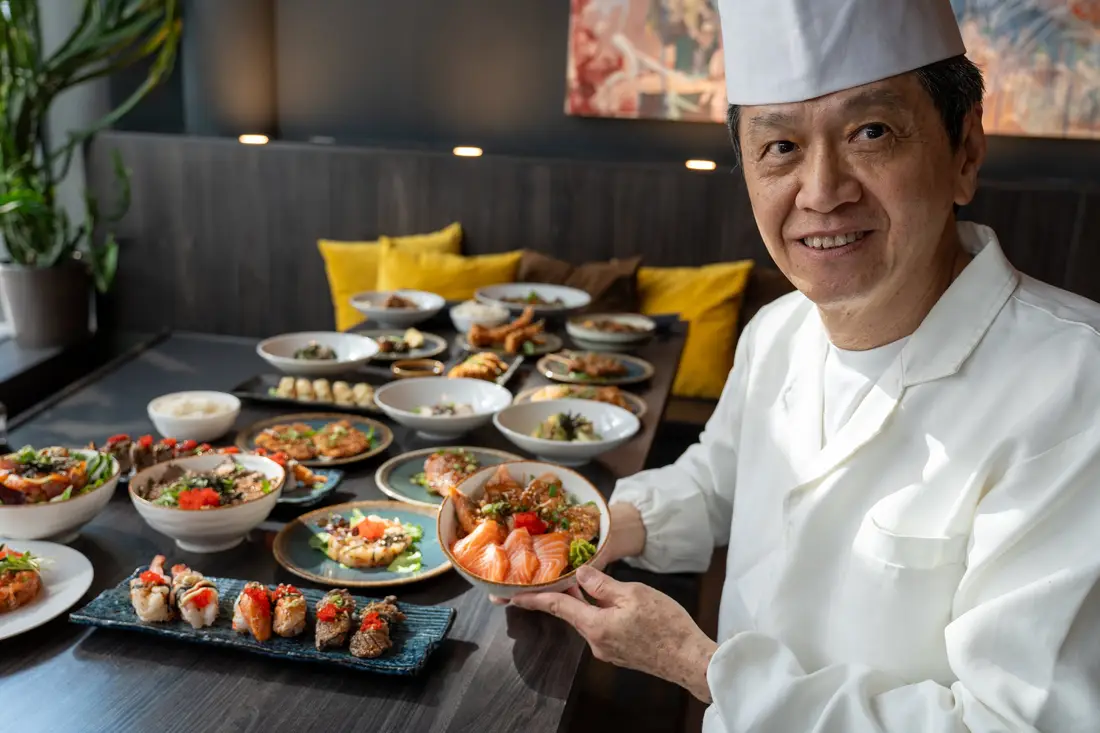 Le maître sushi Robin E.J. Ong devant une table dressée avec sushis, sashimis et bols chez Mikôto Stuttgart